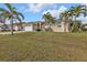 Exterior view showcasing the manicured lawn, tiled roof, and palm trees surrounding the property at 1303 Casey Key Dr, Punta Gorda, FL 33950