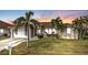 Beautiful home at sunset featuring a manicured lawn, mature palm trees, and a tile roof at 1303 Casey Key Dr, Punta Gorda, FL 33950