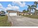 Well-maintained home with a two-car garage, long driveway, and tropical landscaping in a residential area at 1303 Casey Key Dr, Punta Gorda, FL 33950