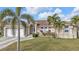 Inviting home featuring a tile roof, arched windows, and a beautifully landscaped lawn with palm trees at 1303 Casey Key Dr, Punta Gorda, FL 33950