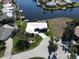 Overhead view of a waterfront property featuring a white roof, driveway, and lush green yard next to a waterway at 1407 Waxwing Ct, Punta Gorda, FL 33950