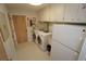 Functional laundry room with washer, dryer, and built-in storage, next to a refrigerator at 1407 Waxwing Ct, Punta Gorda, FL 33950