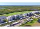 An aerial view of the condo buildings, swimming pool, parking, and golf course surrounded by Florida landscape under a clear sky at 14071 Heritage Landing Blvd # 325, Punta Gorda, FL 33955