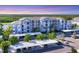 A low aerial view of the light blue condos and parking area surrounded by lush green trees against a colorful evening sky at 14071 Heritage Landing Blvd # 325, Punta Gorda, FL 33955