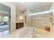 Bright bathroom featuring a soaking tub, and glass enclosed shower with marble tile and natural light at 1492 Aqui Esta Dr, Punta Gorda, FL 33950