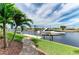 Beautiful waterfront view of the boat dock, lift, and tropical landscaping at 1492 Aqui Esta Dr, Punta Gorda, FL 33950