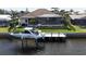 Waterfront view of the home, showcasing the boat dock, landscaped yard, and enclosed pool at 1492 Aqui Esta Dr, Punta Gorda, FL 33950