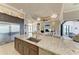 Kitchen island with stainless steel sink, custom cabinets, granite countertop and a view of the open concept living area at 1492 Aqui Esta Dr, Punta Gorda, FL 33950