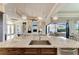 Kitchen island with stainless steel sink, custom cabinets, granite countertop and a view of the open concept living area at 1492 Aqui Esta Dr, Punta Gorda, FL 33950