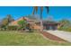 A front exterior of a beautiful tan home, with palm trees, a manicured lawn, and a clean driveway at 1525 Hinton St, Port Charlotte, FL 33952