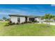 Landscaped front yard featuring a well-maintained lawn, colorful flowers, and a stately palm tree, complementing the home's architecture at 16265 Juarez Cir, Punta Gorda, FL 33955