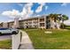 Condo building with a sidewalk, palm trees, and well-maintained green lawn at 175 Kings Hwy # 538, Punta Gorda, FL 33983