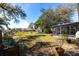 Spacious backyard with lush green grass, mature trees, landscaping, and a glimpse of waterfront access at 18379 Meyer Ave, Port Charlotte, FL 33948