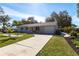 Charming single-story home featuring a well-manicured lawn and concrete driveway, with mature trees in the background at 18379 Meyer Ave, Port Charlotte, FL 33948