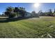 View of the home's large backyard with mature trees, green grass, and the rear of the home at 20262 Hamilton Ave, Port Charlotte, FL 33952