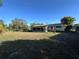 View of the home's backyard, showing the screened patio, lawn, and mature trees at 20262 Hamilton Ave, Port Charlotte, FL 33952
