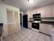 Functional kitchen features neutral cabinetry, black appliances, and easy-to-clean tile flooring at 20262 Hamilton Ave, Port Charlotte, FL 33952