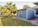 Blue shed with adjacent green grass, gravel, palm trees, and blue skies at 21332 Walling Ct, Port Charlotte, FL 33954