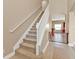 Carpeted staircase with white railings, and beige walls, leading to the upper level of the home at 24528 Sunrise Dr, Punta Gorda, FL 33980
