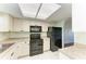 Well-lit kitchen with white cabinets, sleek black appliances, and tile flooring at 3233 Wood Thrush Dr # 23C, Punta Gorda, FL 33950