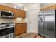 Kitchen with stainless steel appliances, wood cabinets, laminate floors, and view to pantry at 3959 San Rocco Dr # 612, Punta Gorda, FL 33950