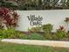 The Village Oaks community sign nestled in a lush flower garden at 623 Oak Hill Cir # 28, Sarasota, FL 34232