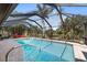 Gorgeous screened-in pool with crystal clear water and outdoor seating, surrounded by lush tropical foliage at 1225 Neapolitan Rd, Punta Gorda, FL 33983