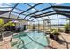 Beautiful screened pool with spa, lush landscaping, and tranquil water views at 1417 Carswell St, Port Charlotte, FL 33953
