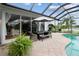 Screened pool patio boasts an outdoor dining set, lush plants, and a view of the water at 1417 Carswell St, Port Charlotte, FL 33953