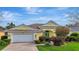 Charming one-story home with a yellow exterior, tile roof, a brick driveway, and meticulously maintained landscaping at 1616 Palmetto Palm Way, North Port, FL 34288