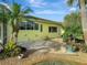 A charming patio area is showcased by tropical landscaping and colorful plants at 1616 Palmetto Palm Way, North Port, FL 34288