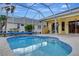 A swimming pool with a screen enclosure, tropical landscaping, and a blue pool cover at 1616 Palmetto Palm Way, North Port, FL 34288