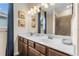 Bathroom featuring double sinks, tiled shower over tub, and beach-themed decor at 17917 Wayside Bnd, Punta Gorda, FL 33982