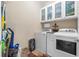 Laundry room with white washer and dryer, upper storage cabinets, and cleaning supplies at 17917 Wayside Bnd, Punta Gorda, FL 33982