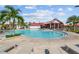A luxurious outdoor swimming pool with lounge chairs, umbrellas, and a clubhouse at 17917 Wayside Bnd, Punta Gorda, FL 33982