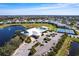 Aerial view of the community clubhouse, pool, tennis courts, parking, and a scenic pond at 2081 Willow Hammock Cir # F101, Punta Gorda, FL 33983