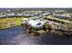 An aerial view of a clubhouse, pool, and tennis courts next to a dark colored pond at 2081 Willow Hammock Cir # F101, Punta Gorda, FL 33983