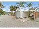 Exterior view of garage, with a corrugated metal door, attached carport, and surrounding palm trees at 23475 Harper Ave, Port Charlotte, FL 33980