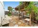 This backyard shows a stone-covered ground with a wooden pergola with metal roof covering and hanging lighting at 23475 Harper Ave, Port Charlotte, FL 33980