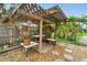 The backyard has a stone-covered ground, and a wooden pergola featuring hanging potted plants and lighting at 23475 Harper Ave, Port Charlotte, FL 33980