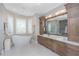 Bright bathroom with a soaking tub, double vanity, white countertops, and wood cabinets at 24362 Peppercorn Rd, Punta Gorda, FL 33955