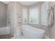 Modern bathroom with a glass shower featuring mosaic tile, a soaking tub and plantation shutters at 24362 Peppercorn Rd, Punta Gorda, FL 33955
