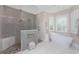 Modern bathroom with a glass shower featuring mosaic tile, a soaking tub and plantation shutters at 24362 Peppercorn Rd, Punta Gorda, FL 33955