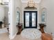 Elegant foyer with double front doors, chandelier, wood flooring, area rug and art display at 24362 Peppercorn Rd, Punta Gorda, FL 33955