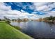 Beautiful lake view with green lawn, trees, and blue skies with white clouds at 24362 Peppercorn Rd, Punta Gorda, FL 33955