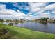 Scenic lake view with lush green lawns, trees, and blue skies with puffy white clouds at 24362 Peppercorn Rd, Punta Gorda, FL 33955