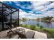 Screened-in patio with lounge chairs overlooks a serene lake and well-manicured landscaping at 24362 Peppercorn Rd, Punta Gorda, FL 33955