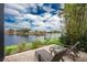 Screened-in patio with lounge chairs overlooks a serene lake and lush tropical landscaping at 24362 Peppercorn Rd, Punta Gorda, FL 33955