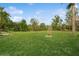 A lush green lawn surrounded by a variety of trees and foliage fills the backyard space at 3213 Normandy Dr, Port Charlotte, FL 33952
