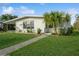 Charming single-story home with lush green lawn, sidewalk, and a unique patterned wall accent at 3213 Normandy Dr, Port Charlotte, FL 33952